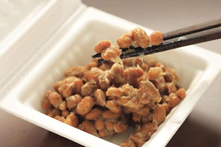 パック入りの納豆を箸で混ぜている