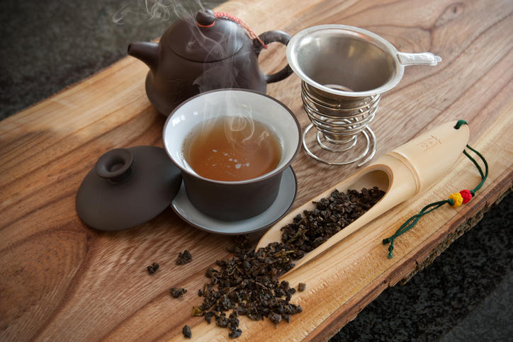 木製テーブルに置かれたカップ入りの烏龍茶と茶葉や茶器