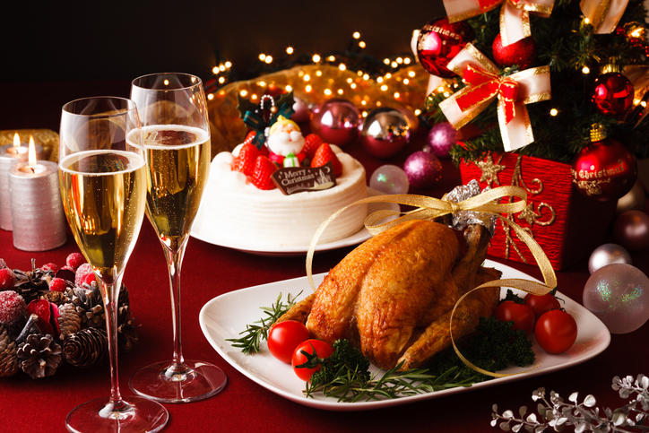 ローストチキンとクリスマスケーキとグラスに注がれたシャンパン