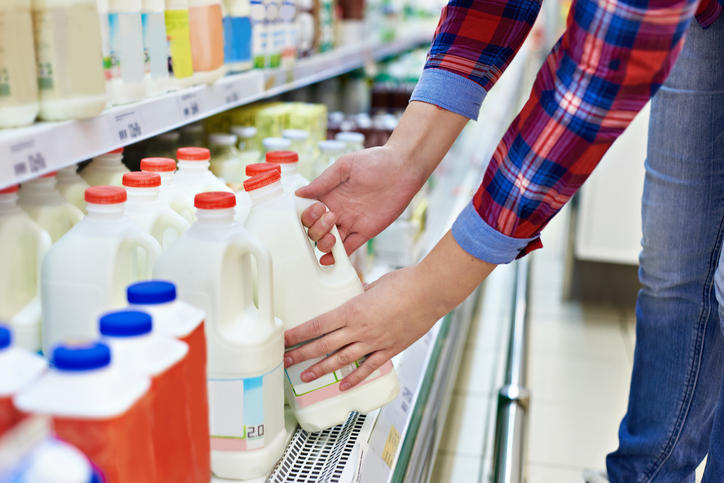 シャツを着た人が冷蔵庫から牛乳を手に取っている