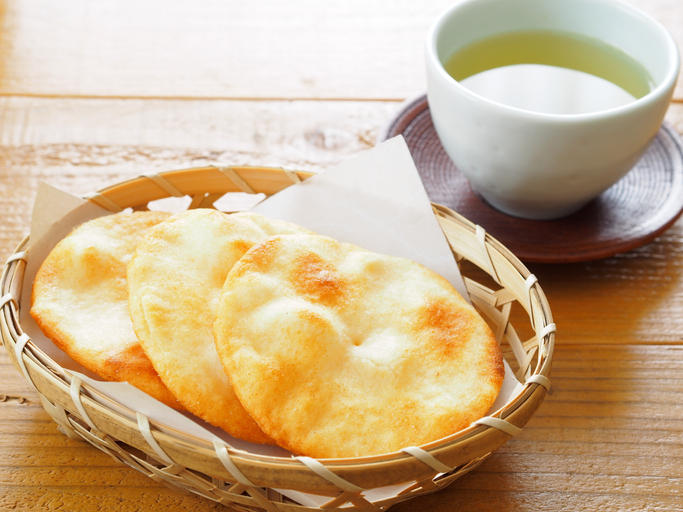 竹製のかごに入ったせんべい、お茶がテーブルに置かれている