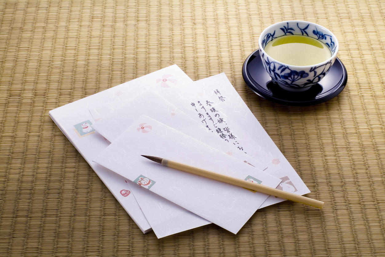 畳の上にある白い便箋と封筒、筆、お茶