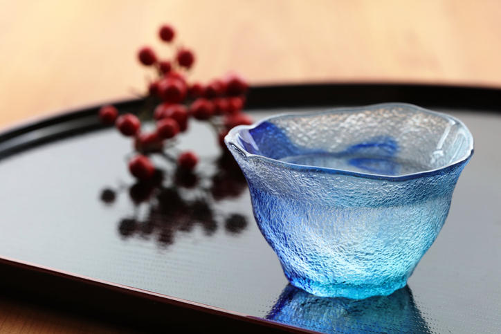 黒いトレイの上に置かれた日本酒入りの水色のグラス