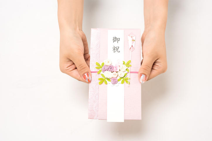 ピンク色のご祝儀袋を両手で手渡そうとしている