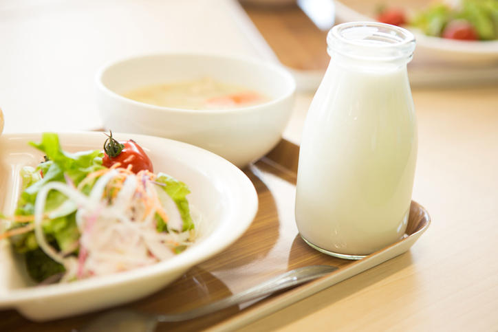 給食のトレイに野菜とあわせて牛乳瓶が置かれている