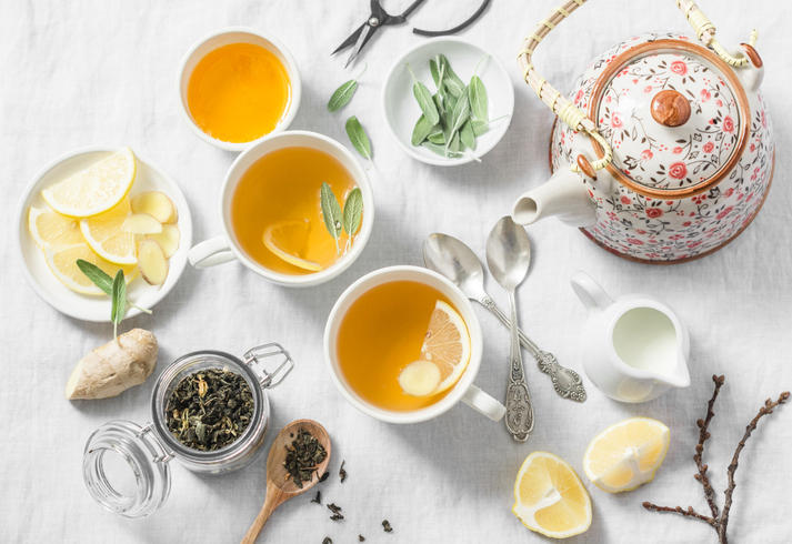 花柄のティーポットと紅茶が入ったふたつのティーカップ、柑橘、茶葉