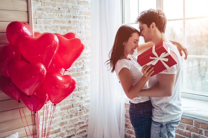 プレゼントを贈り、抱き合う男女とハートの風船