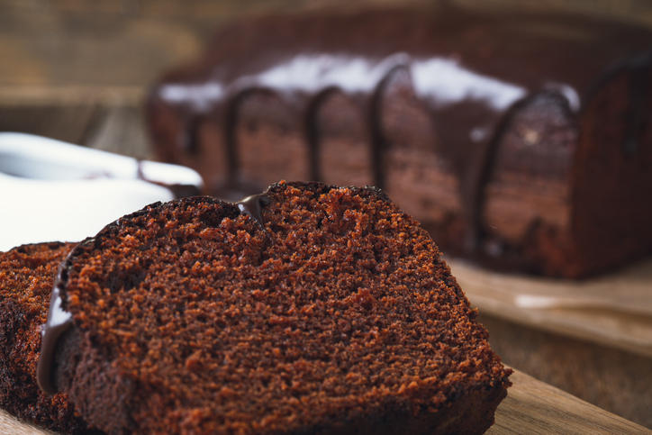 木製のカッティングボードに置かれたチョコレートパウンドケーキとスライスされたケーキ