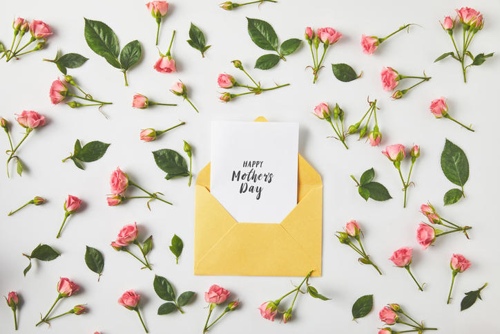 薔薇の花と葉がランダムに置かれた白い背景の上の母の日のグリーティングカード