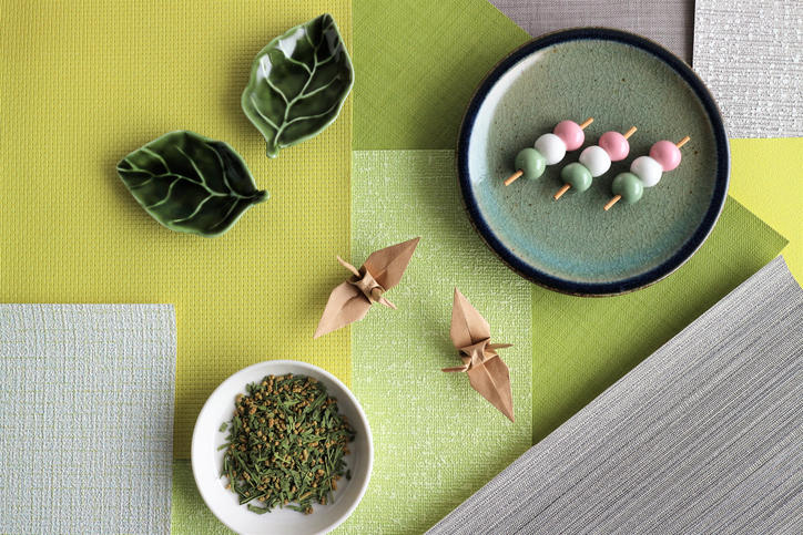 丸皿に盛られた3本の三色団子と白い皿に盛られたお茶っ葉