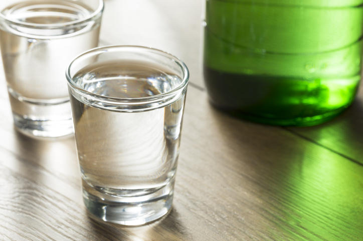 グラスに入った焼酎と傍らに緑色の瓶