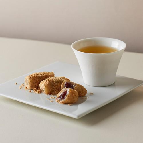 白いトレイに置かれた黄金餅と白いコップ入りのお茶