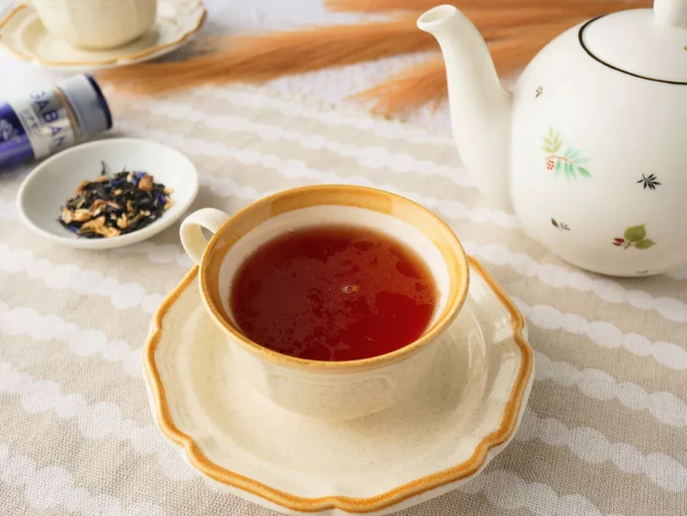 シナモンティーが注がれたティーカップと花柄のティーポットと茶葉が入れられた小皿が置かれている