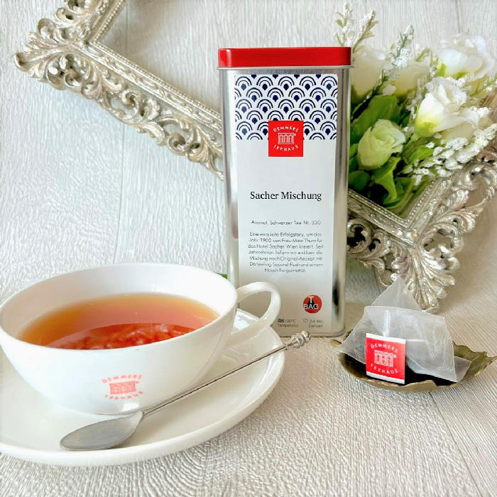 デンメアティーハウスザッハブレンドの紅茶缶と、紅茶が注がれた白いカップが置かれている