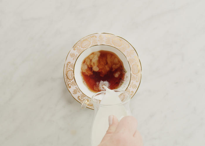 紅茶がはいったピンクのティーカップに紅茶が注がれている