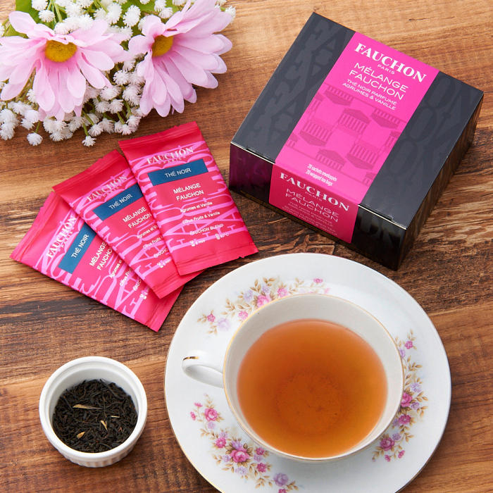 フォションブレンドのティーバッグと紅茶が注がれた花柄のティーカップとピンクのフラワーアレンジが置かれている