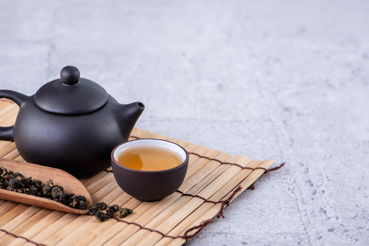 黒い茶壺と烏龍茶が注がれた茶杯と茶葉が置かれている