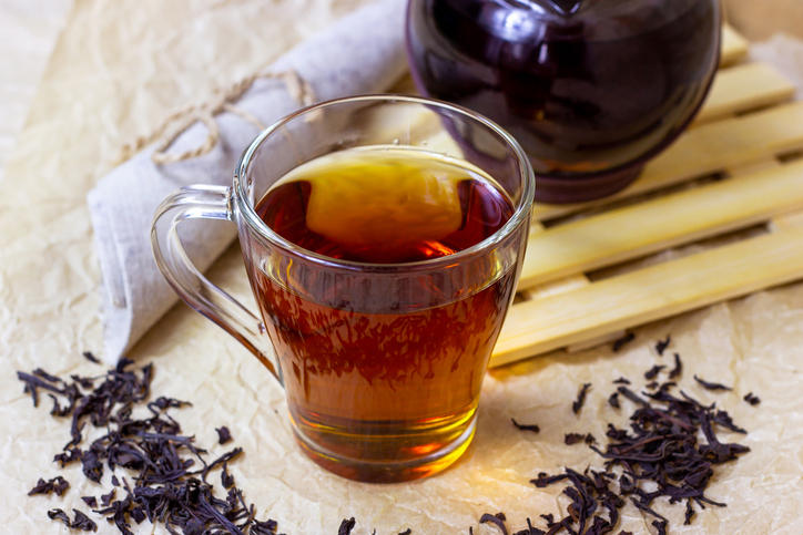 紅茶が注がれたガラスのカップと茶葉とティーポットが置かれている