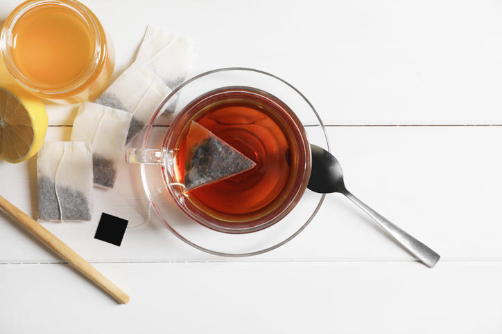 白い木のテーブルにティーバッグでいれた紅茶が入ったガラスのカップが置かれている
