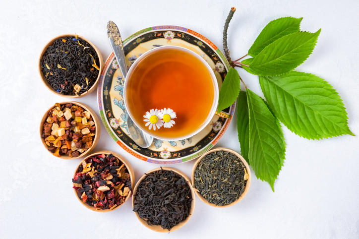 紅茶が注がれた花柄のティーカップと、5種類の茶葉が置かれている