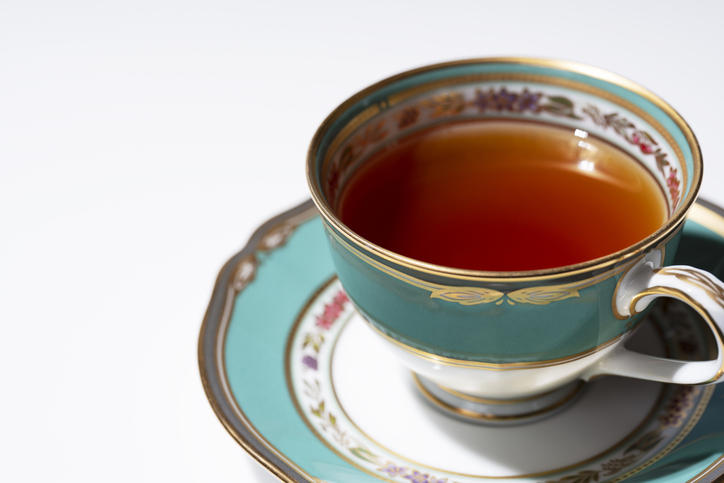 ブルーグリーンのアンティークのティーカップに紅茶が注がれている