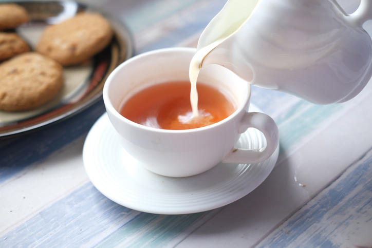 白いティーカップにいれられた紅茶に牛乳が